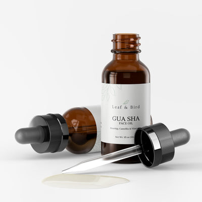Gua Sha Face Oil bottle open with the black dropper beside it