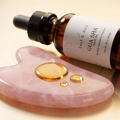 Gua Sha Face Oil texture: golden oil drops on a rose quartz gua sha stone
